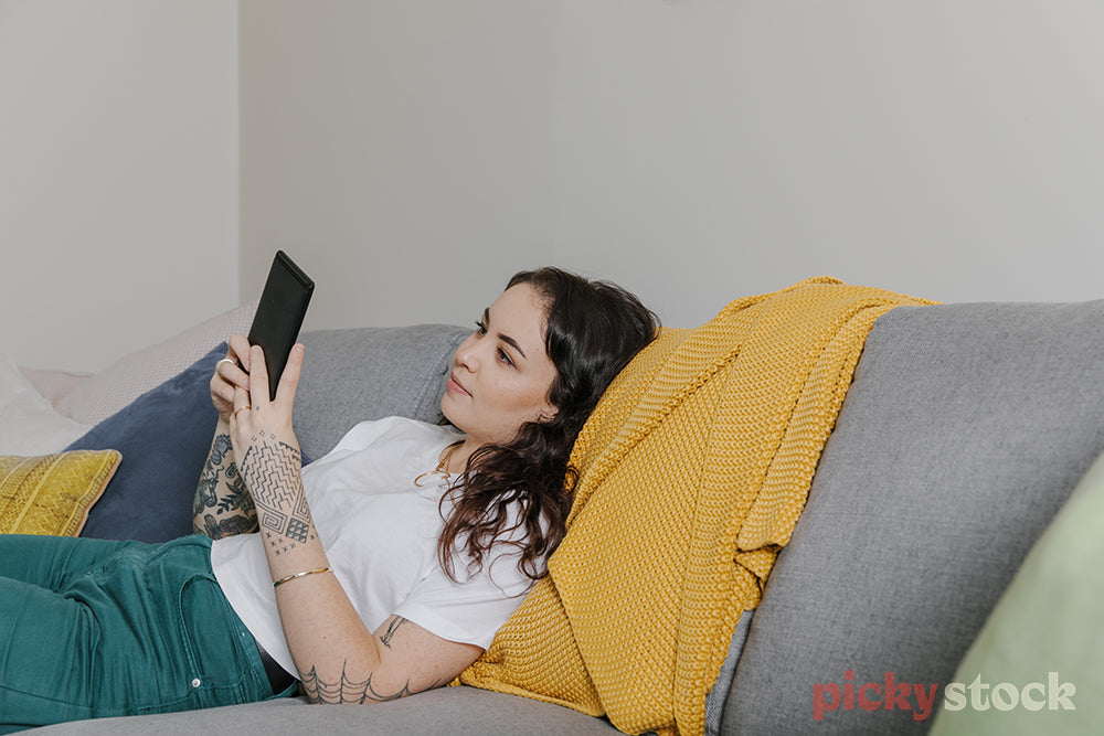 Female chilling on couch reading from kindle