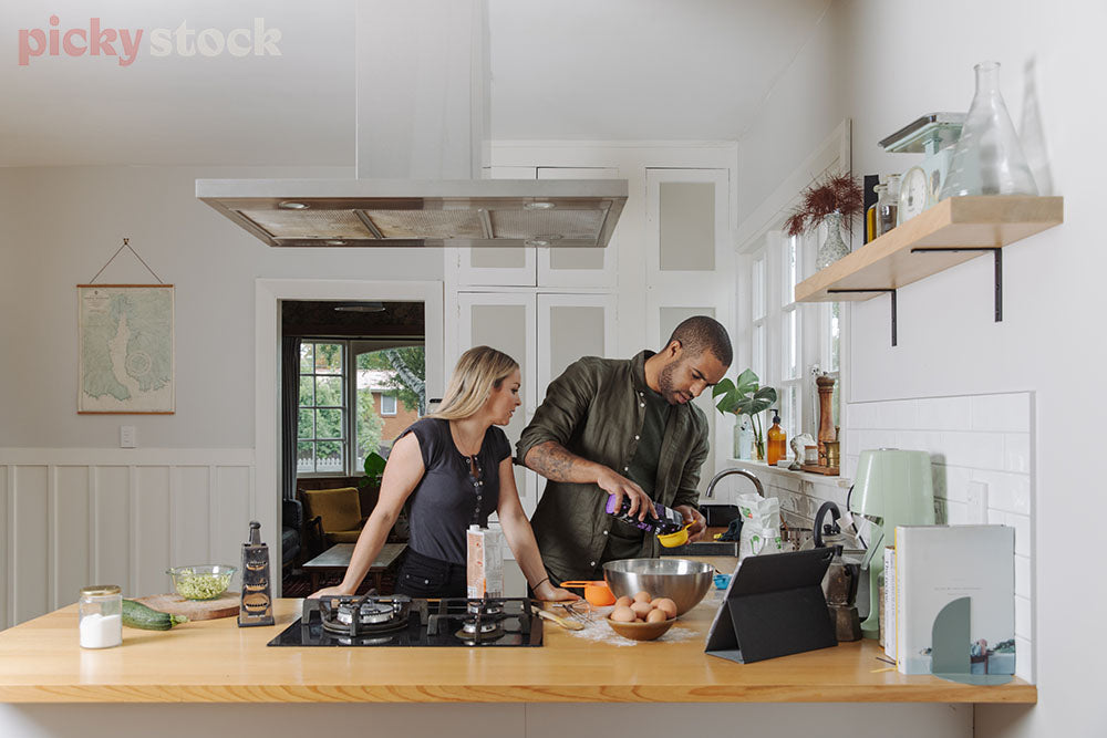 A couple cook using a digital recipe in modern kiwi kitchen. 