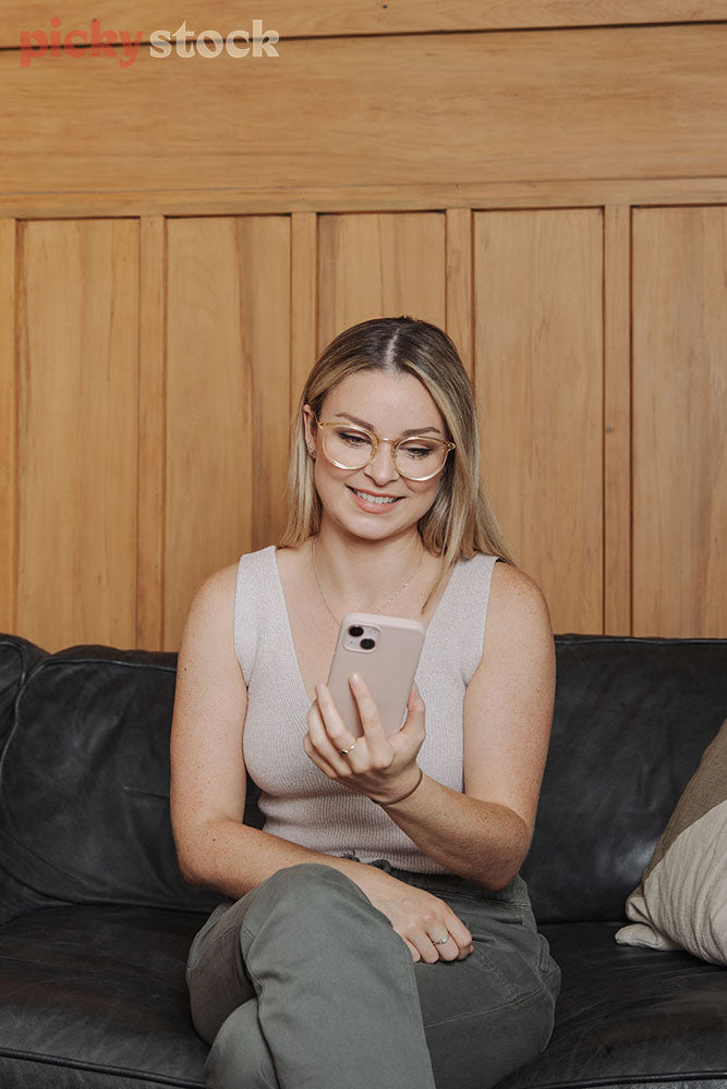 Woman sitting on couch looking at mobile phone. 