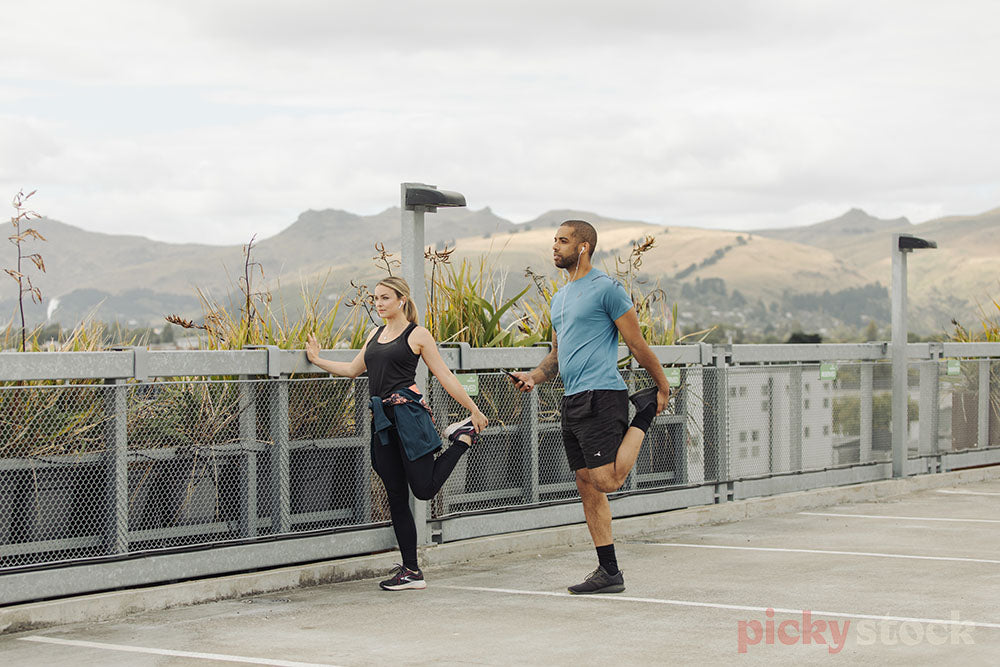 Couple stretching in  Christchurch carpark before run.