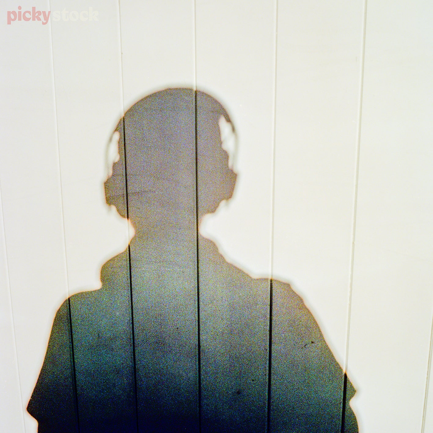 Colourful shadow of a person wearing headphones on white wood wall 