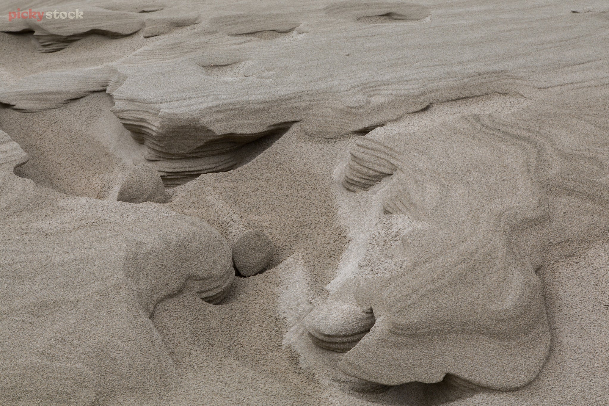 Landscape close up of sand dune eroding into striated cliffs and valleys.