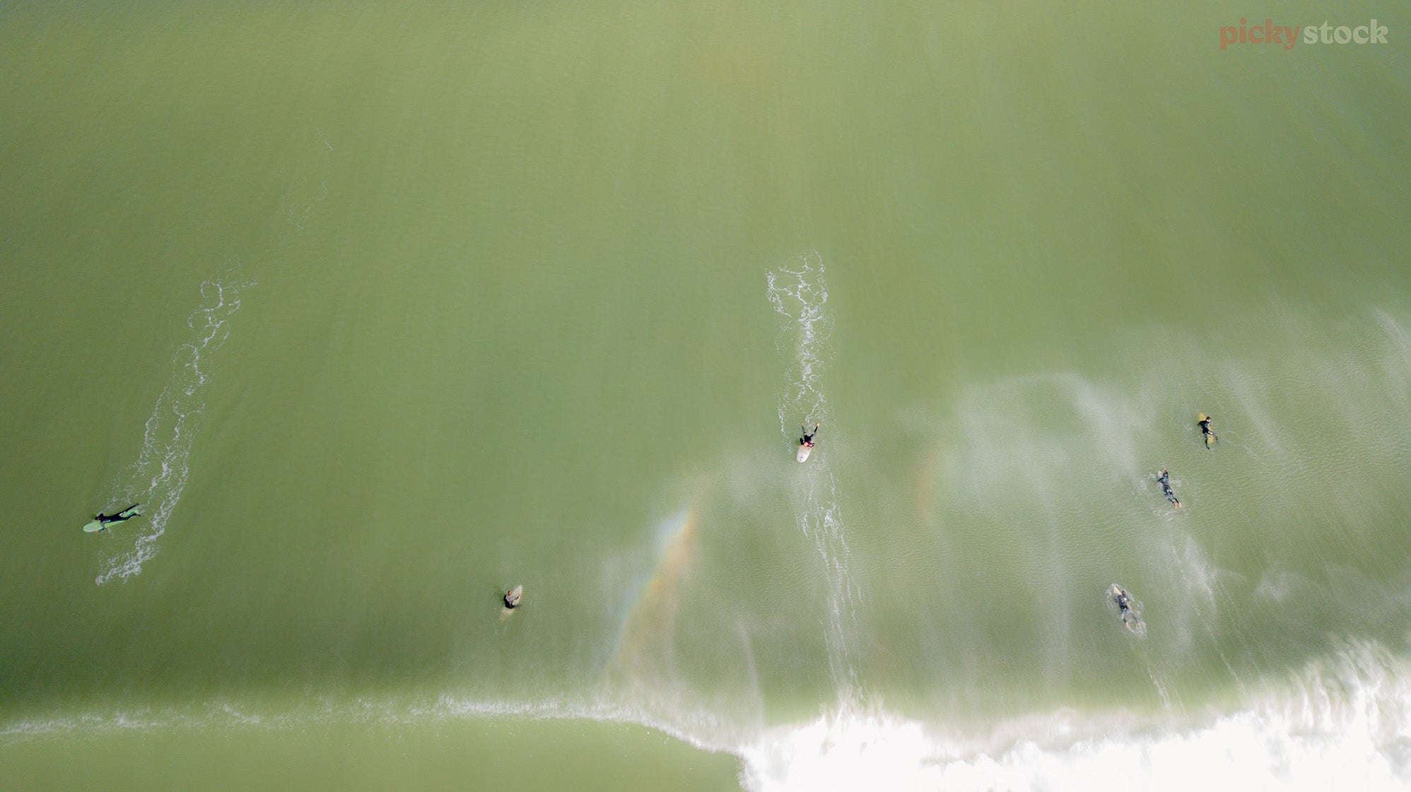 Six surfers on NZ waves, seen from above.