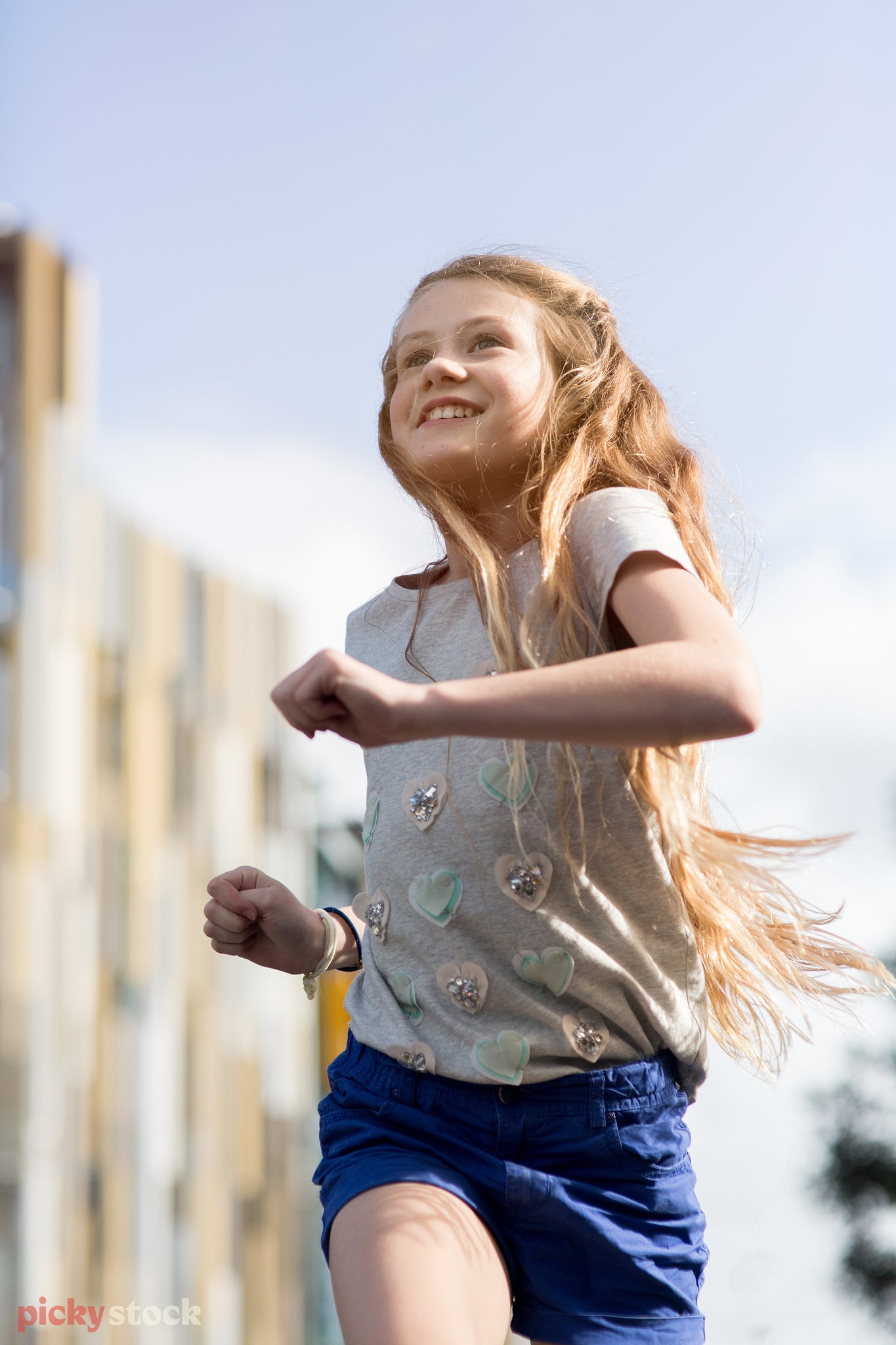 Portrait of a young girl running, the background is blurred as the sunlight cast small beams on her face.