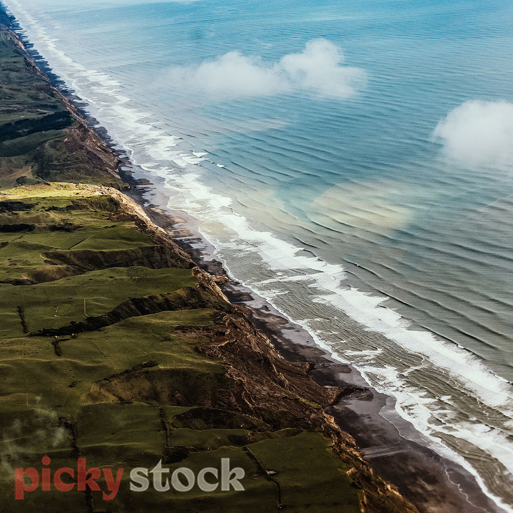 Canterbury coast aerial where the land and cliffs meet the sea. The waves slowly rolling on in. 