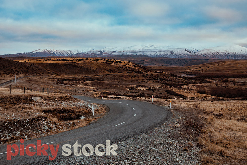 Looking down winding open road out towards ice capped mountains. 