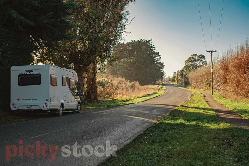 Caravan parked up to the left of a Canterbury road, in the shade from the bright light. 