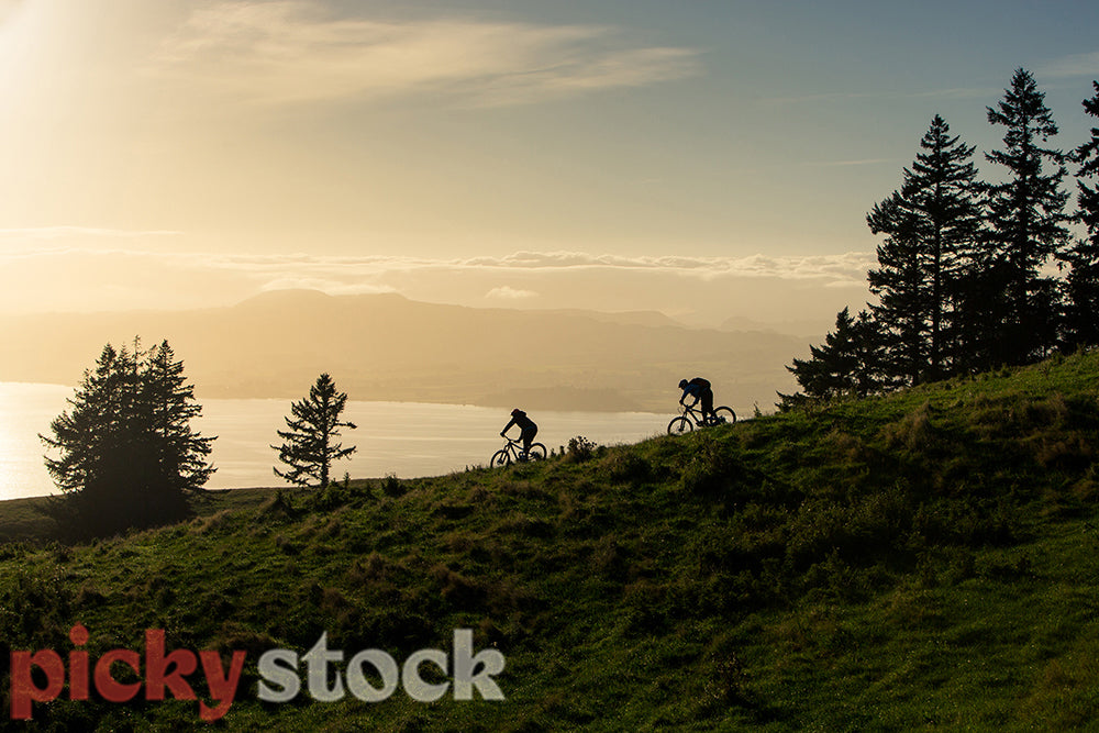 Mountain bikers riding down a ridge in the sunrise
