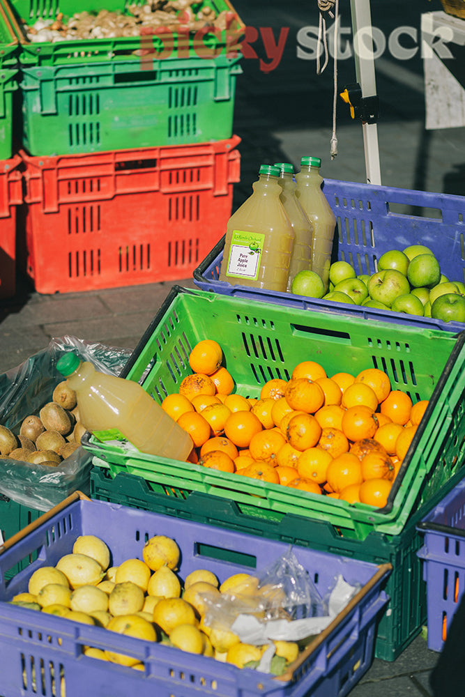 Colourful plastic crates at inner city farmers market selling lemons and oranges.