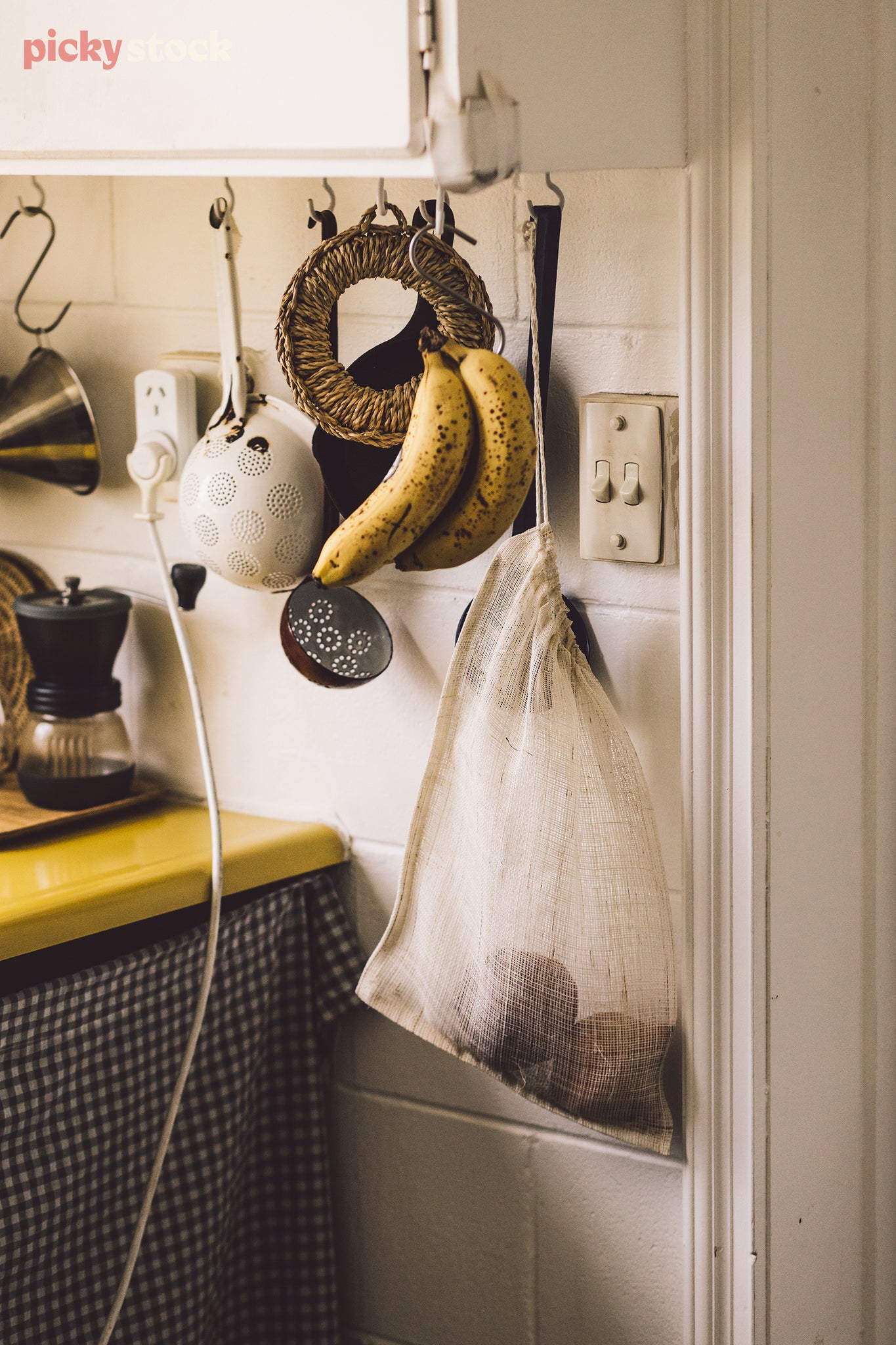 A string re-usable shopping bag hangs in a kitchen, doused in sunlight. 